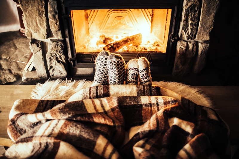 couple with a blanket next to the fireplace.