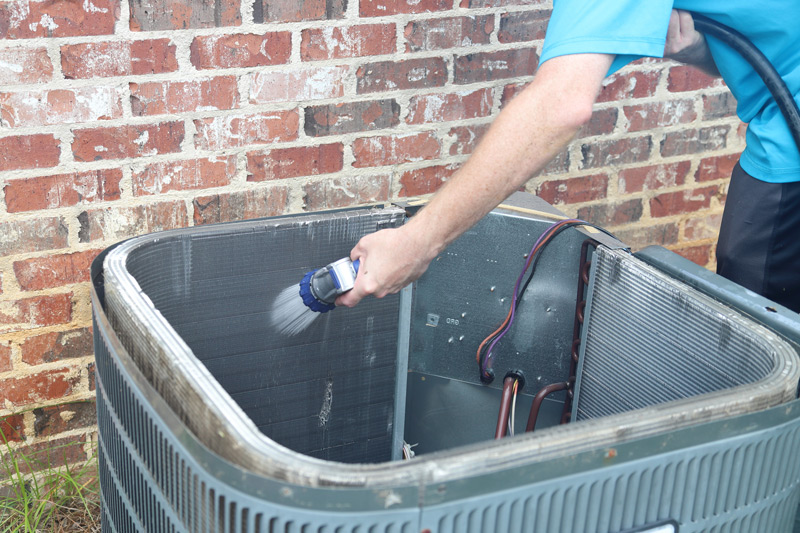 An hvac tech cleaning an outdoor AC unit for Spring.